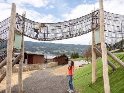 Kind klettert auf einem Netzspielgerät, Frau steht unten und schaut nach oben