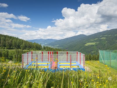 Ein Trampolinbereich mit bunten Sprungmatten inmitten einer Berglandschaft.