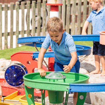 Kinder spielen am bunten Wasserspielplatz mit Wasser