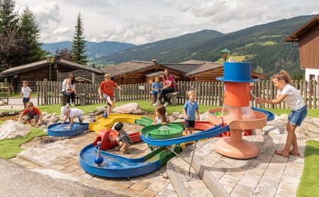 Einige Kinder spielen am bunten Wasserspielplatz im Freien