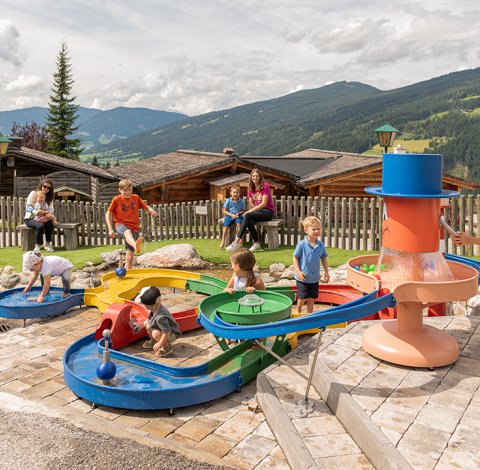 Einige Kinder spielen am bunten Wasserspielplatz im Freien