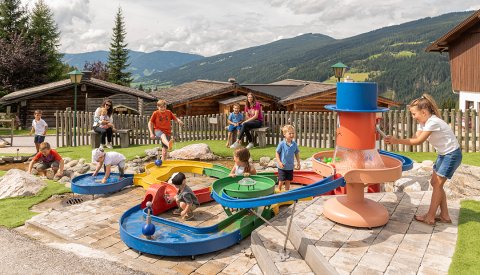 Einige Kinder spielen am bunten Wasserspielplatz im Freien