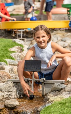 Mädchen spielt mit Wasser am felsigen Wasserspielplatz