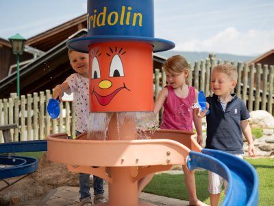 Three kids happily play with water at "Fridolin" station | © Drei Kinder spielen fröhlich mit Wasser an Station „Fridolin“