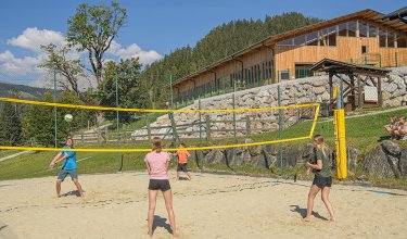 Kinder spielen Beachvolleyball im Sand.