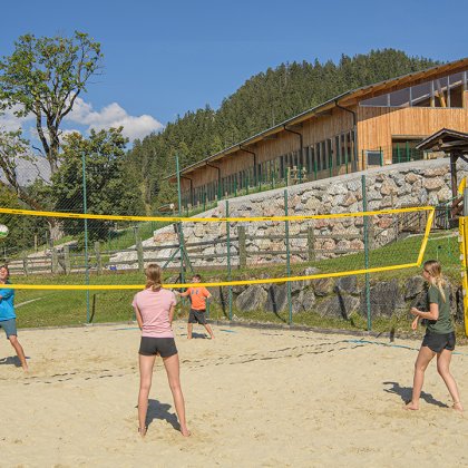 Kinder spielen Beachvolleyball im Sand.