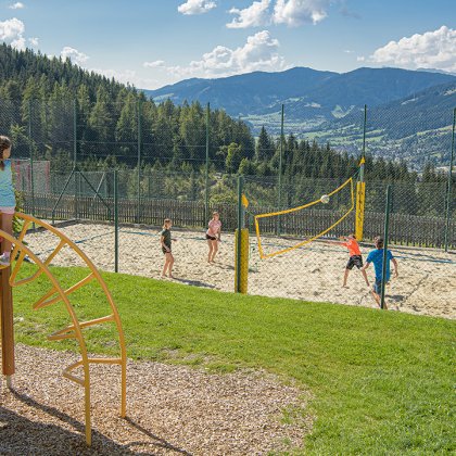 Kinder spielen Volleyball und auf einem Spielplatz.