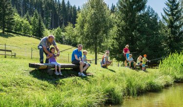 Familie und Kinder genießen gemeinsam das Angeln am Teich.