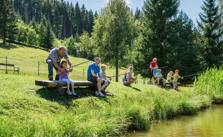Familie und Kinder genießen gemeinsam das Angeln am Teich.