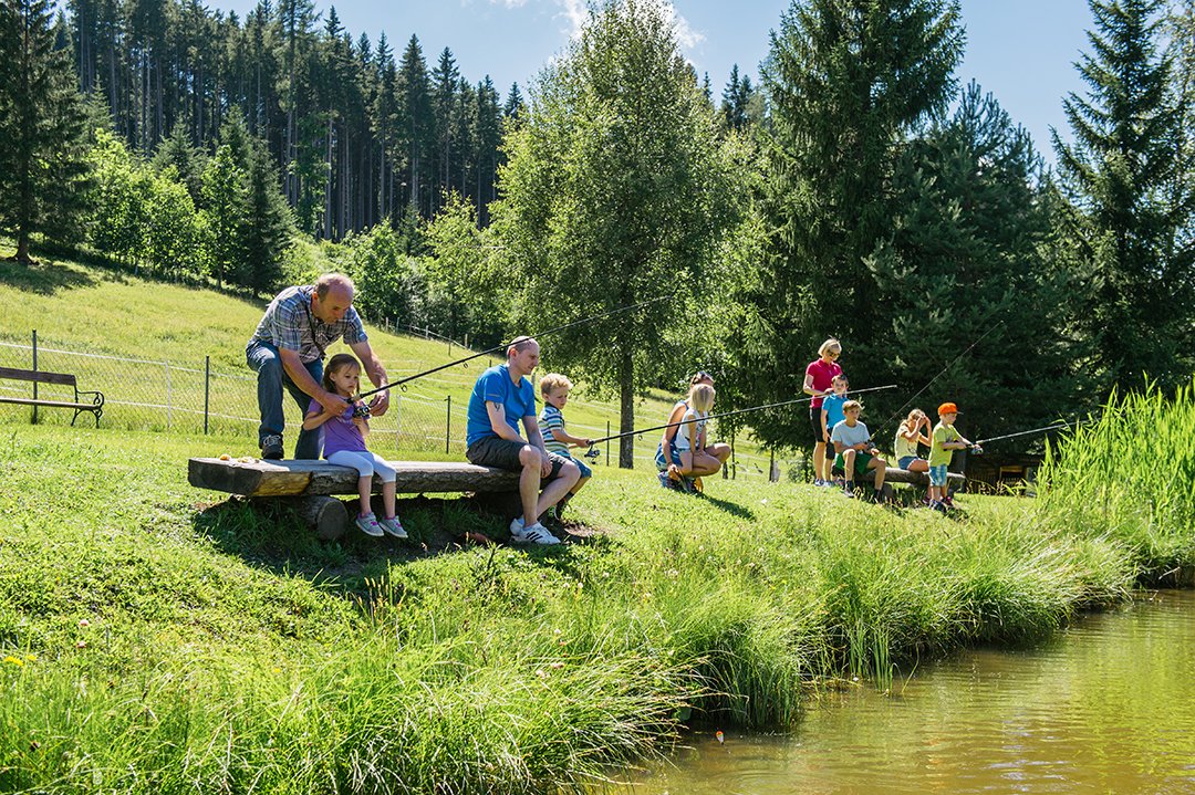 Familie und Kinder genießen gemeinsam das Angeln am Teich.
