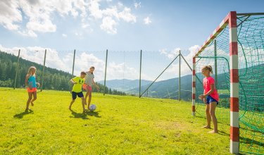Kinder spielen gemeinsam Fußball im Freien.