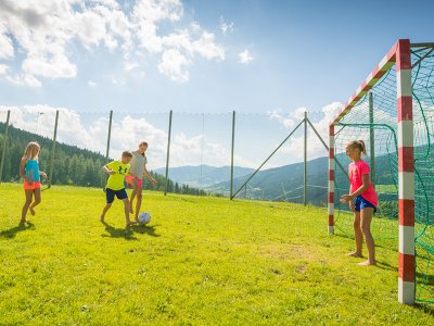 Kinder spielen gemeinsam Fußball im Freien.