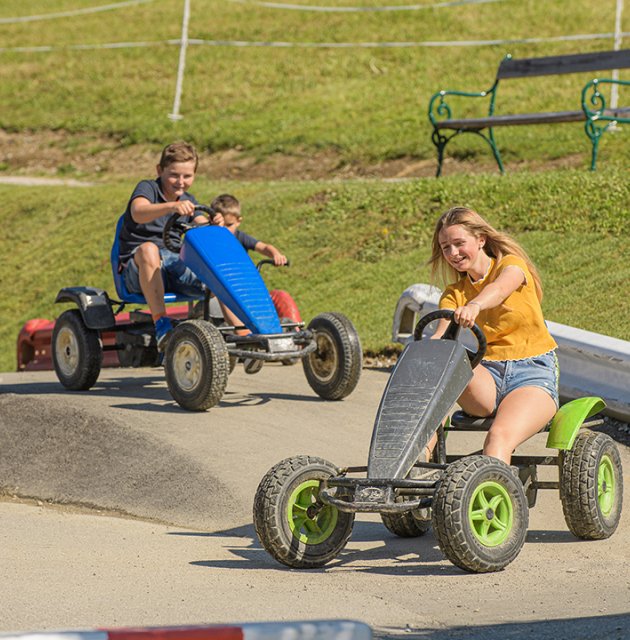 Kinder fahren mit Kettcars auf einem Parcours.