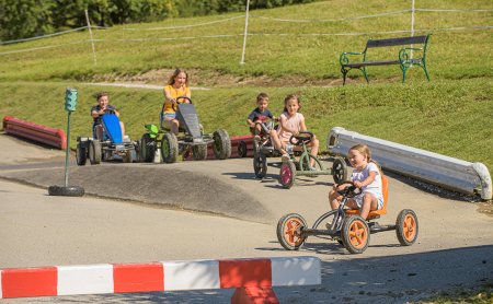 Kinder fahren mit Kettcars auf einem Parcours.
