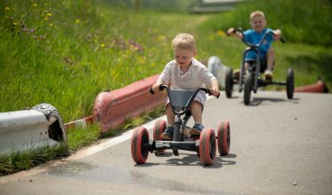 Jungen fahren auf Go-Kart eine kurvige Straße entlang