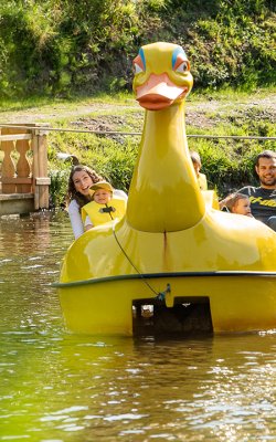 Familie genießt eine Fahrt im gelben Enten-Tretboot auf dem Teich.