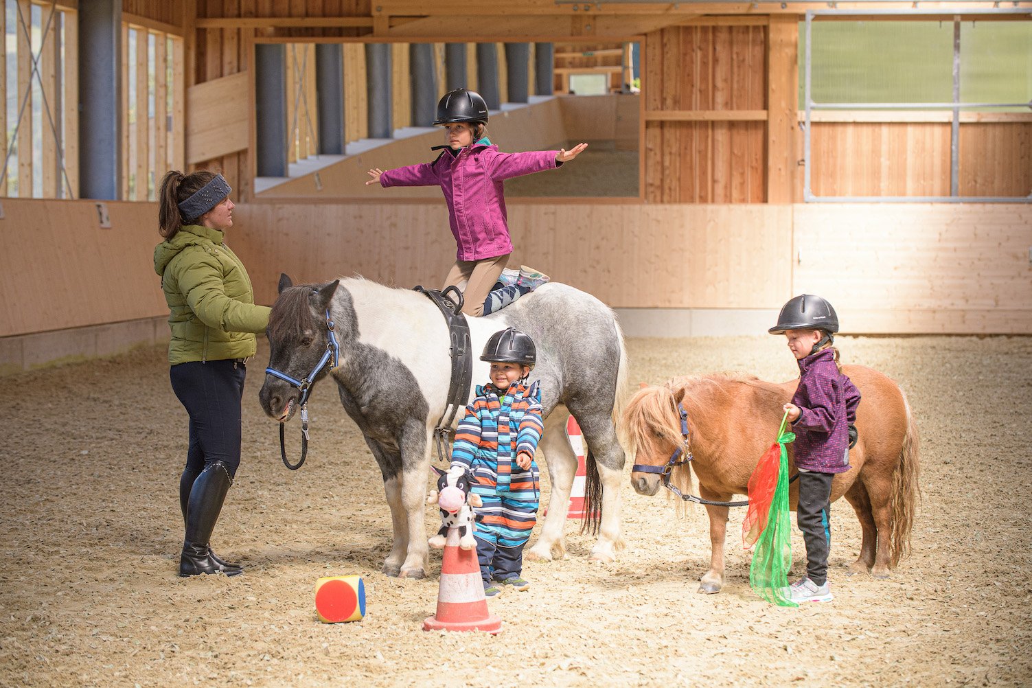 Kinder üben Voltigieren und Ponyführen in der Reithalle.
