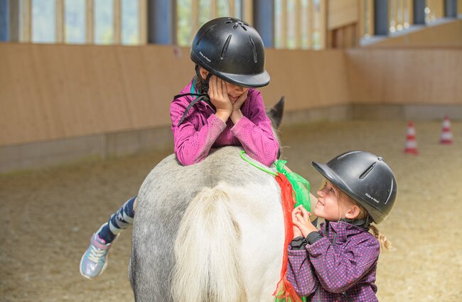 Kinder haben Spaß beim Reiten auf dem Pony