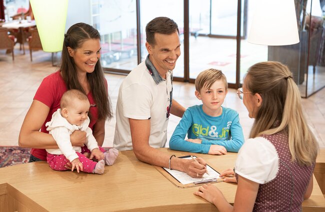 Familie an der Rezeption mit der Gastgeberin