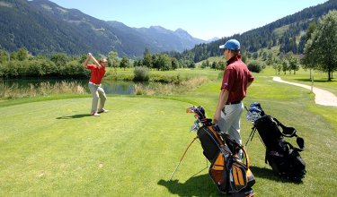 Zwei Golfer spielen auf einem Berggolfplatz bei strahlendem Wetter.