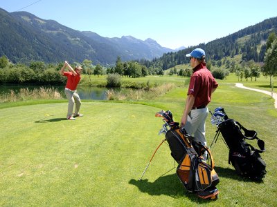 Zwei Golfer spielen auf einem Berggolfplatz bei strahlendem Wetter.
