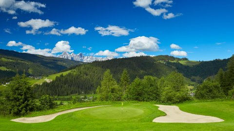 Golfgreen mit Sandbunkern vor beeindruckender Alpenkulisse.
