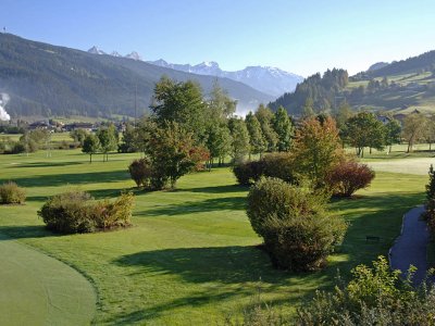 Golfplatz mit viel Grün und Bergpanorama an einem klaren Morgen.