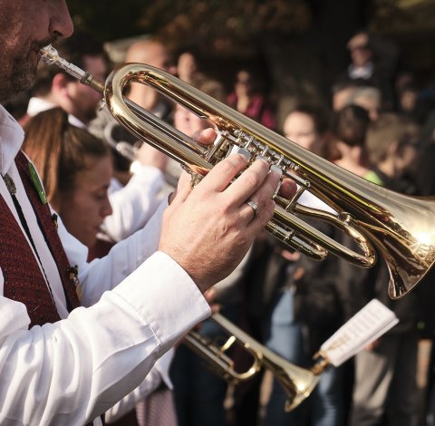Musiker in Tracht spielt Trompete bei einer Veranstaltung im Freien.