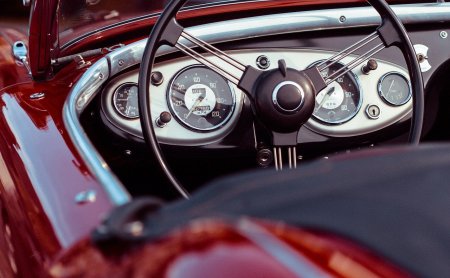 Cockpit eines roten Oldtimers mit klassischen Instrumenten.