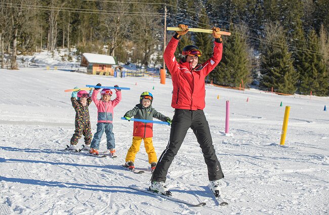 Skilehrer zeigt Kindern etwas vor