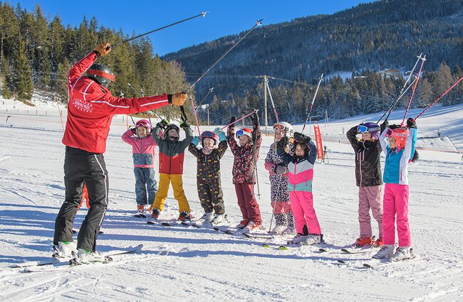 Skilehrer animiert die Skikursgruppe