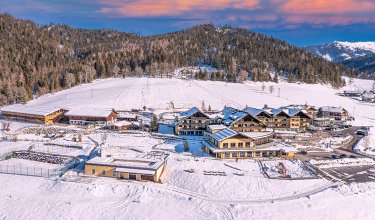 Winterresort in verschneiter Alpenlandschaft bei Sonnenuntergang.
