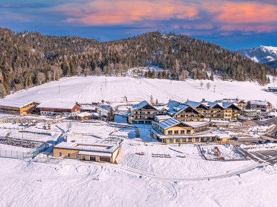 Winterresort in verschneiter Alpenlandschaft bei Sonnenuntergang.