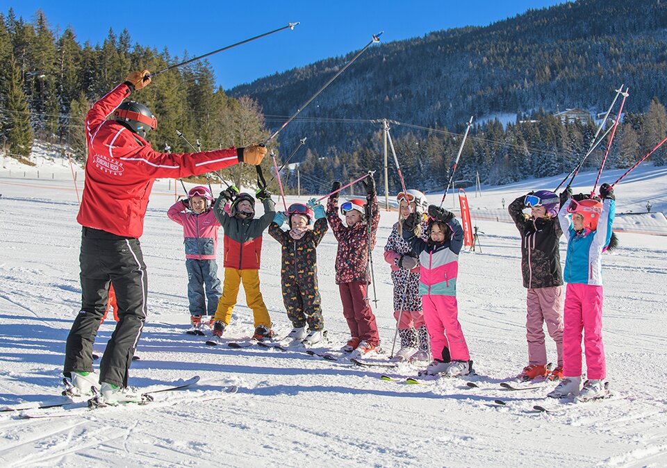 Skilehrer animiert die Skikursgruppe