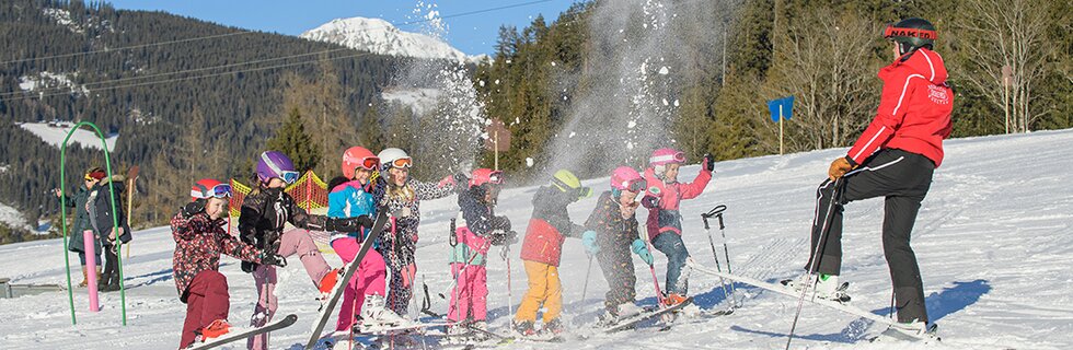 Skilehrer und Skikursgruppe haben Spaß im Schnee