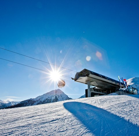 Gondel an Bergstation bei Sonnenschein und klarem Himmel.