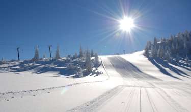 Frisch präparierte Skipiste unter strahlender Wintersonne.