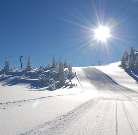 Frisch präparierte Skipiste unter strahlender Wintersonne.