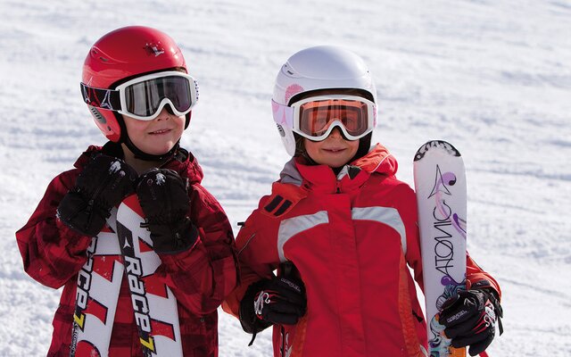 Kinder mit Skiern beim Kinderskikurs