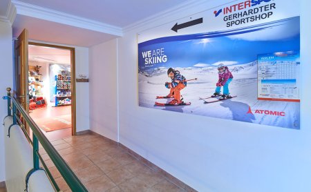 Wegweiser zum Skiverleih und Shop mit Blick durch offene Tür.