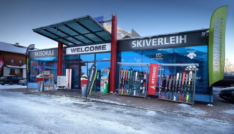 Eingangsbereich von Skischule und Verleih mit ausgestellten Skiern.