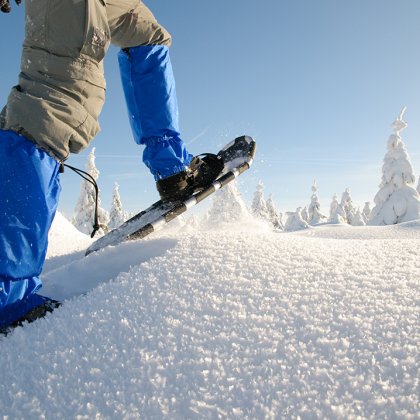 Schneeschuhwandern durch tiefen Schnee an einem Sonnentag.