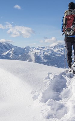 Wanderer mit Schneeschuhen genießt den Panoramablick auf Berge.