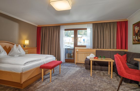 Geräumiges Doppelzimmer mit Sitzecke, Balkonzugang und gemütlicher Einrichtung.