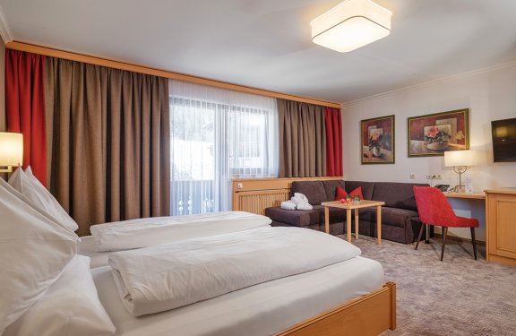 Komfortables Doppelzimmer mit Sofa, Schreibtisch und Zugang zum eigenen Balkon.