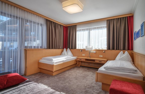 Gemütliches Zimmer mit zwei Einzelbetten, großen Fenstern und Holzmöbeln.
