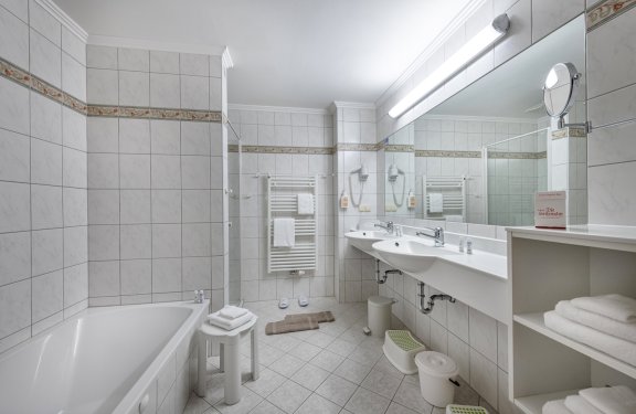 Helles Bad mit Badewanne, Doppelwaschbecken und großem Wandspiegel.