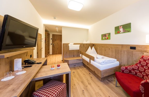 Modernes Kinderzimmer mit zwei Einzelbetten, Holzmöbeln und Katzenbildern.