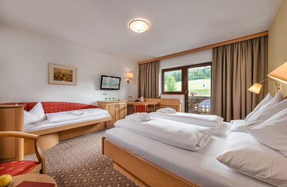 Komfortables Familienzimmer mit Doppelbett, Schlafsofa und Balkon mit Naturblick.