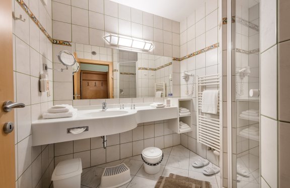 Helles Bad mit Dusche, großem Spiegel und praktischer Ausstattung.